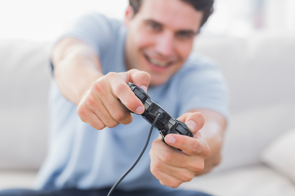 Portrait of a smiling man playing video games in his living room-1